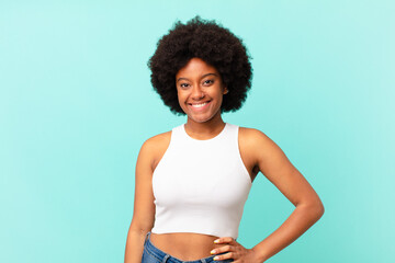 afro black woman smiling happily with a hand on hip and confident, positive, proud and friendly...