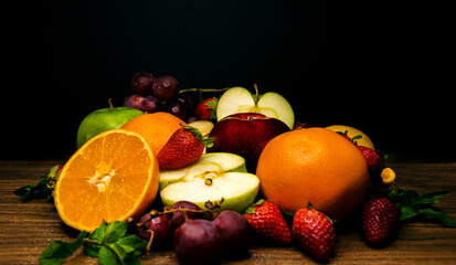 fresh fruits on a wooden board on a black background
