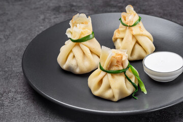 Hinkali with sour cream on the black plate