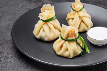 Hinkali with sour cream on the black plate