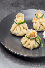 Hinkali with sour cream on the black plate