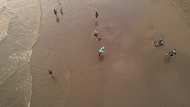 sandy beach parangtritis near ocean with big waves, people in tropical resort at sunset. Yogyakarta, Indonesia. aerial view seascape, ocean and beautiful beach. Travel concept. Indonesia, java
