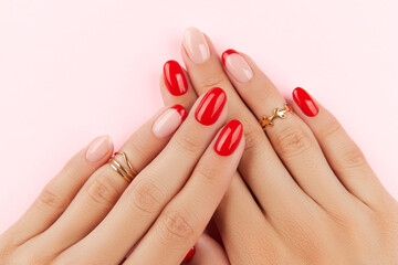 Womans hands with red modern manicure over pink background. Manicure design trends - obrazy, fototapety, plakaty