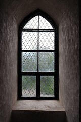 Narrow glazed window in the thick stone wall of the old castle