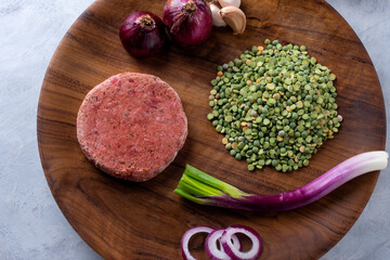 Fototapeta na wymiar vegan and vegetarian black bean burger with raw peas beet green onion garlic purple onion pepper on wooden plate for healthy eating
