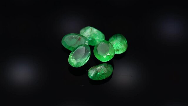 natural green emerald on the turning table on the black background
