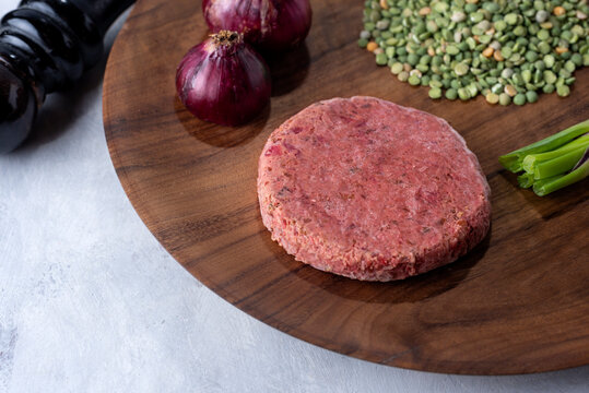 vegan and vegetarian black bean burger with raw peas beet green onion garlic purple onion pepper on wooden plate for healthy eating