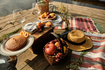 Romantic picnic by the river. The beauty of the setting sun, fresh fruits, pastries and wine. A romantic outdoor dinner.