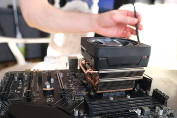 hands of young male master install cooler with copper heat pipes for the processor, other parts of pc into case, the concept of repairing equipment, assembling, upgrading a personal computer