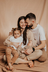 A young sincere family where a stylish bearded father and a cute wife hold their cute children in...