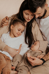 A young sincere family where a stylish bearded father and a cute wife hold their cute children in...