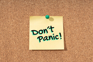 Dont panic message on yellow note on cork board