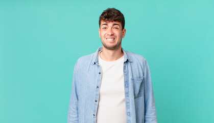 handsome man looking puzzled and confused, biting lip with a nervous gesture, not knowing the...
