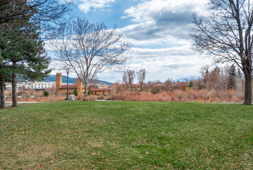 Fototapeta na wymiar A woman relaxes at a public park along the Clark Fork River with downtown Missoula, Montana, USA seen in the distance.