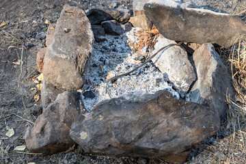 Gray and brown big stones and white ash in a fireplace in the forest