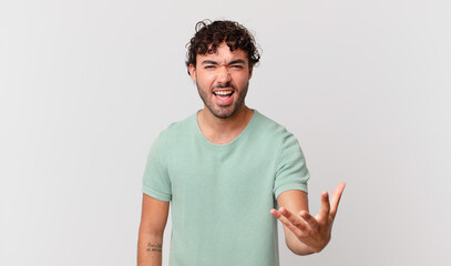 hispanic handsome man looking angry, annoyed and frustrated screaming wtf or what’s wrong with you