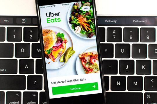 Uber Eats Food Ordering And Delivery Mobile App Is Opened On A Smartphone. MacBook Pro Touch Bar Shows Delivery And Delivered Words. - San Jose, California, USA - 2020