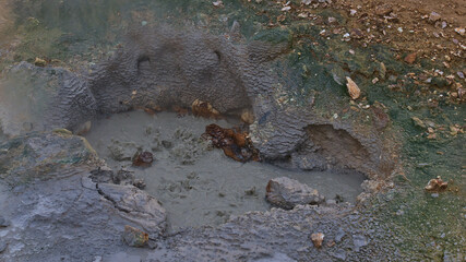 Closeup view of bubbling mud pot with spraying hot water at geothermal area Seltún, part of volcanic system Krýsuvík, with on Reykjanes peninsula, Iceland with rocks.