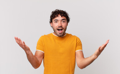 hispanic handsome man feeling happy, excited, surprised or shocked, smiling and astonished at...