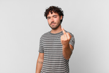 hispanic handsome man feeling angry, annoyed, rebellious and aggressive, flipping the middle...