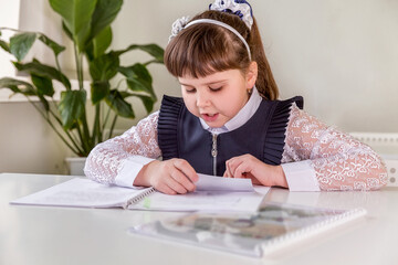 A girl pupul  sits at  a desk in the classroom and reads a book. Back to school concept