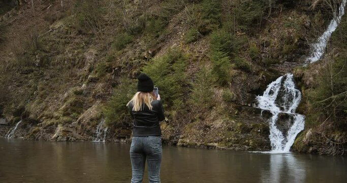 Girl tourist is photographed against the background of a waterfall in the Carpathians