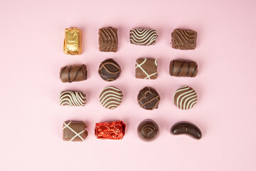 top view of various chocolate pralines on pink background. Collection chocolates candy. Assorted...