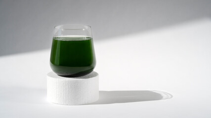 Healthy spirulina chlorella drink in the glass on podium or pedestal. Modern style. Superfood,...