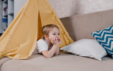 a large portrait of a little girl lying inside a yellow teepee