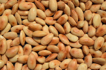 Freshly roasted almonds with salt background pattern closeup