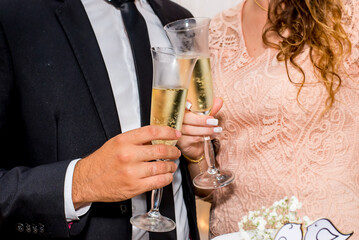 Hands of newlyweds toasting with glasses of champagne.