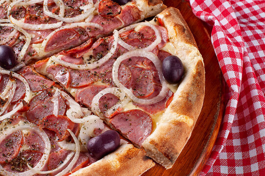 .Brazilian style pizza with mozzarella cheese, pepperoni sausage and onion. Top view