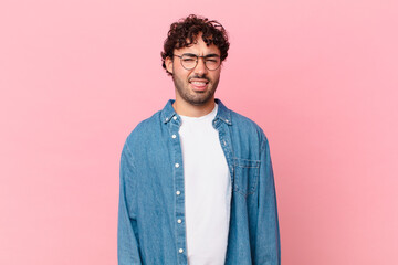 hispanic handsome man feeling disgusted and irritated, sticking tongue out, disliking something...
