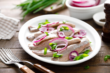 Pickled herring fillet with onion on plate