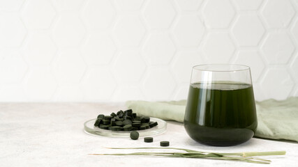 Obraz na płótnie Canvas Healthy spirulina drink in the glass with spirulina chlorella pills. Superfood, detox drink. Healthy care concept.