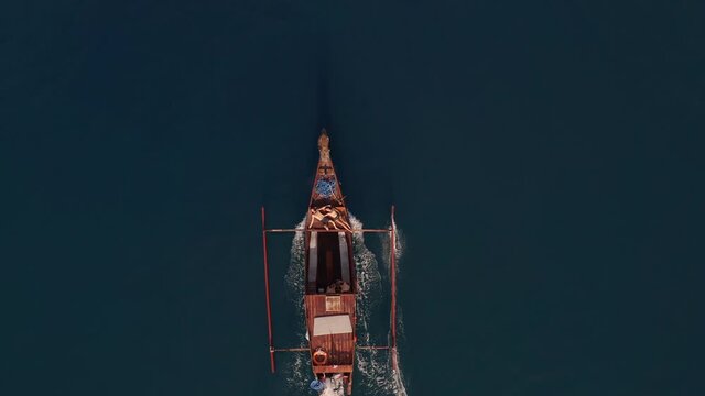 Aerial view rising above a Jukung boat on the calm sea - birdseye, drone shot