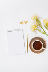 Mockup white notebook, yellow irises and cup with coffee on a white background