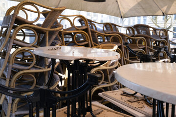 Chairs and tables stacked on top of each other under a restaurant awning. It is closed due to the lockdown due to corona in the Netherlands.
Focus on the edge of the table to the left