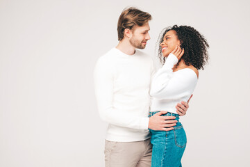 Smiling beautiful woman and her handsome boyfriend. Happy cheerful multiracial family having tender moments on grey background  in studio. Multiethnic models hugging. Embracing each other.Love concept