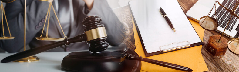 Justice and law concept.Male judge in a courtroom with the gavel, working with, computer and docking keyboard, eyeglasses, on table in morning light