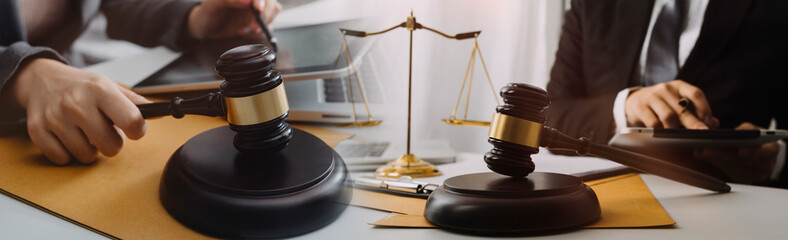 Justice and law concept.Male judge in a courtroom with the gavel, working with, computer and docking keyboard, eyeglasses, on table in morning light