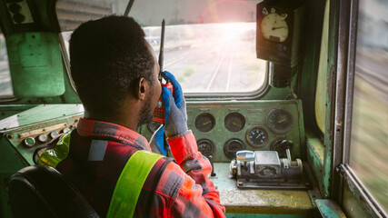 African train driver talking radio communication or walkie talkie in  interior room to control...