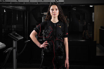 Fototapeta na wymiar Girl in EMS suit in gym. Sport training in electrical muscle stimulation suit.