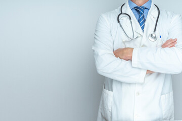 DOCTOR WITH STETHOSCOPE, WHITE COAT AND FOLDED ARMS. TRUSTED DOCTOR AND HEALTH INSURANCE CONCEPT. COPY SPACE.
