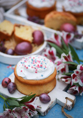 Easter. Spring. Easter cake with colored eggs, flowers on white wooden boards on a blue table. Background image, copy space, vertical