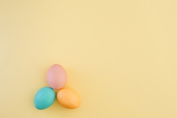 Minimalistic background with colorful Easter eggs and copy space. Pastel Easter eggs in pink, blue and yellow. Beautiful Easter composition. Top view, flat lay