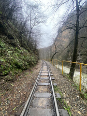 Close up of railway in mountainous terrain. Railway track in rainy weather in amazing and mysterious nature.
