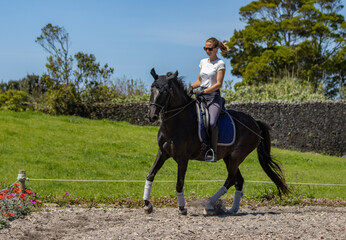 Happy woman riding black Lusitano horse, beautiful mare, outdoors.