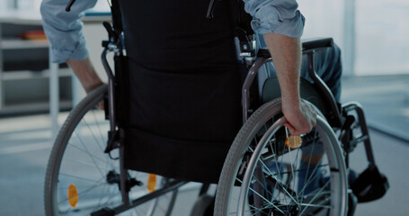 Obraz premium Young man in black wheelchair moving along the corporate office. Employee business person with disabilities entering office to start work.