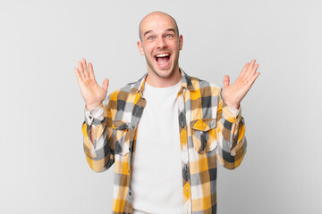 bald man feeling happy, excited, surprised or shocked, smiling and astonished at something...